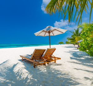 Zwei Liegest&uuml;hle mit Sonnenschirm an einem wei&szlig;en Sandstrand in Sri Lanka, umgeben von Palmen und t&uuml;rkisfarbenem Meer.