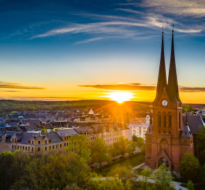Blick auf die Markuskirche in Chemnitz bei Sonnenuntergang mit zwei markanten Kircht&uuml;rmen vor einer malerischen Altstadtkulisse.