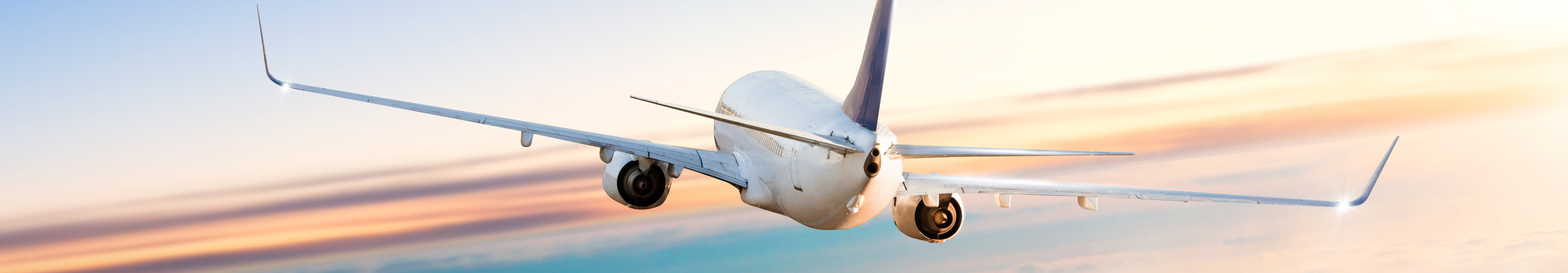 Flugzeug fliegt &uuml;ber Wolken bei dramatischem Sonnenuntergang