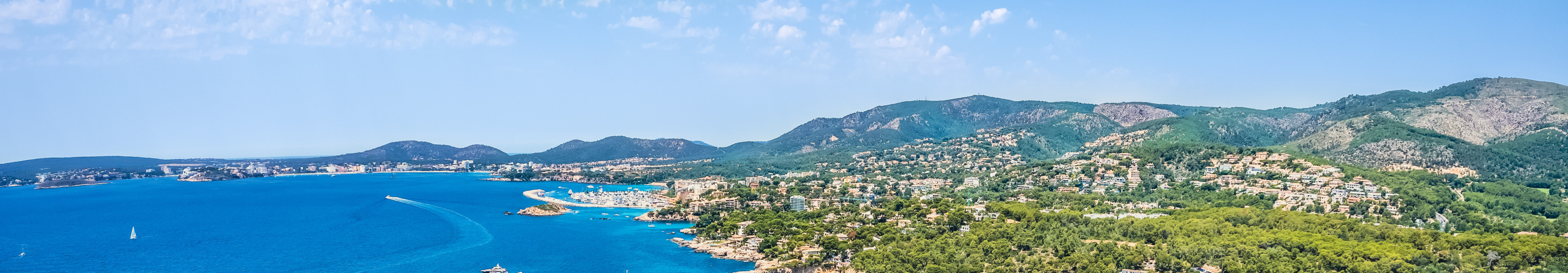 Luftaufnahme der Küste von Mallorca mit türkisblauen Buchten, Segelbooten und grünen Hügeln