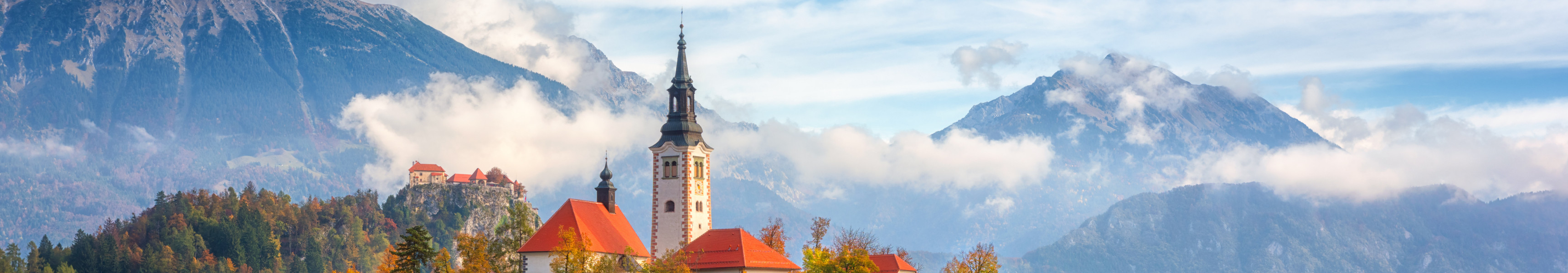 Malerischer Blick auf den Bleder See, Insel mit Kirche, Burg Bled, Berge und blauer Himmel mit Wolken