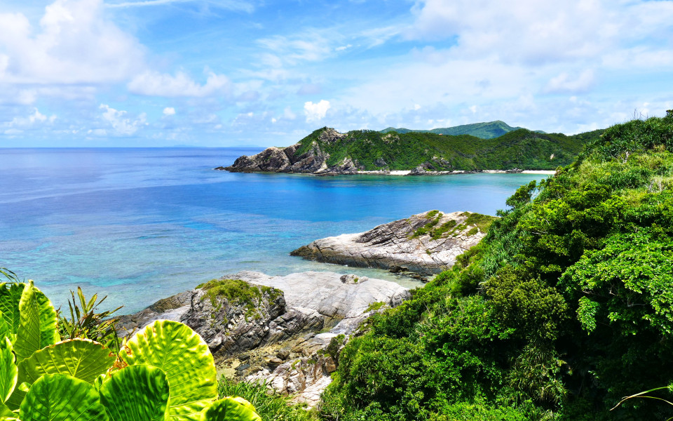 Tropisches Paradies mit gr&uuml;nen H&uuml;geln, wei&szlig;em Sand, t&uuml;rkisfarbenem Meer und tiefblauem, sonnigem Himmel in Zamami, Okinawa, Japan