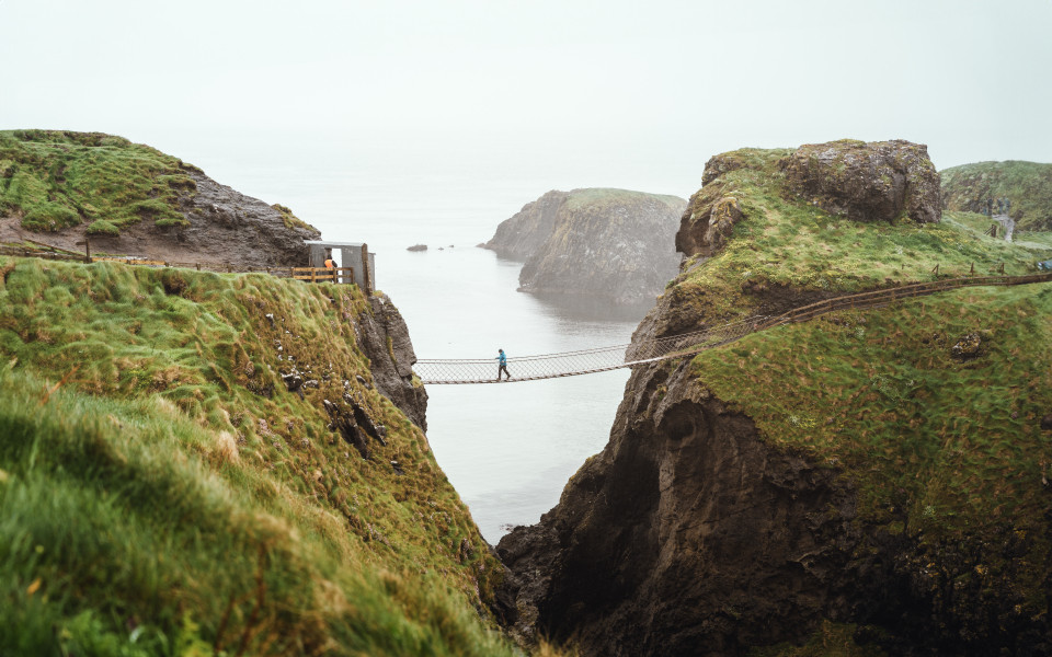 Frau in blauer Regenjacke an der Carrick-A-Rede H&auml;ngebr&uuml;cke.