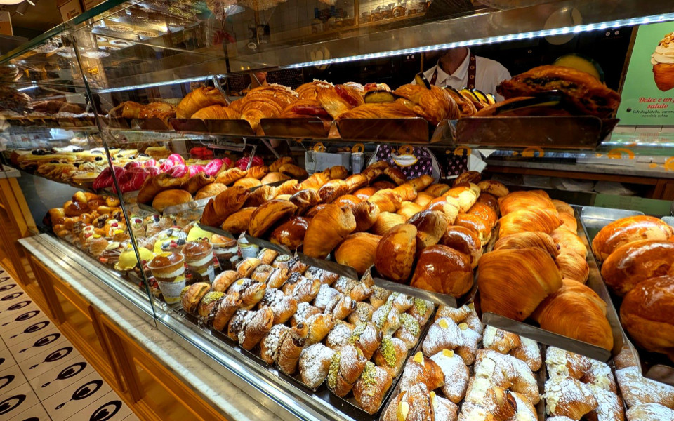 Auslage einer Pasticceria in Neapel mit gef&uuml;llten Cornetti, Sfogliatelle, Geb&auml;ck mit Puderzucker und weiteren italienischen S&uuml;&szlig;speisen.