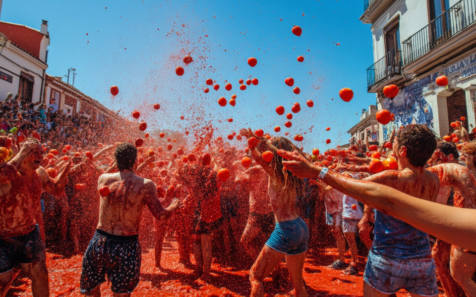 Menschen auf den Straßen bewerfen sich mit roten Tomaten bei dem Fest La Tomatina in Spanien