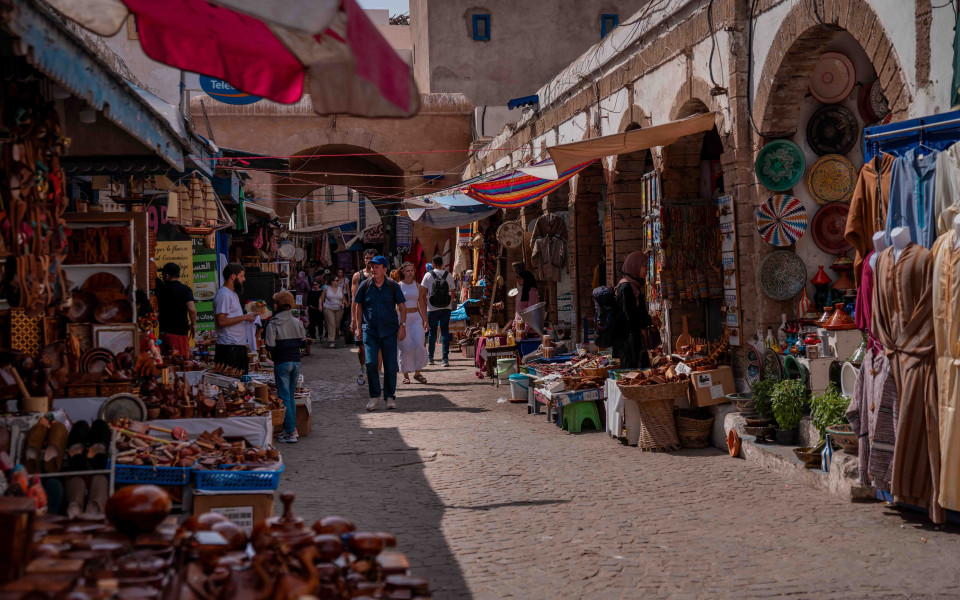 Belebter Souk in der Altstadt von Essaouira mit bunten Marktständen, traditionellen Handwerkswaren und schlendernden Touristen.