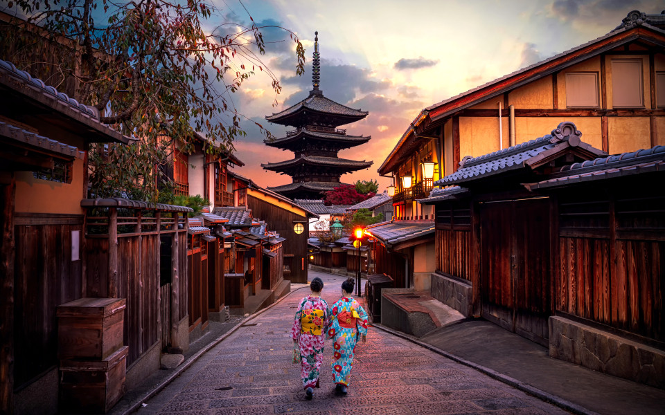 Zwei Geishas in traditionellen japanischen Kimonos zwischen der Yasaka-Pagode und der Sannen-Zaka-Straße in Kyoto, Japan.